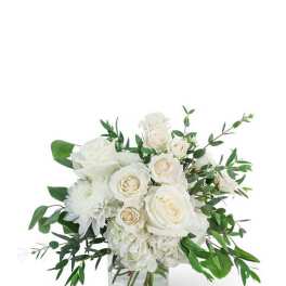White roses and mums in a clear glass vase with greenery