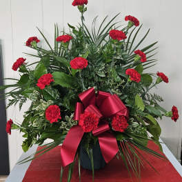 Red carnations in a vase with a large red ribbon