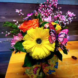 Bright mixed bouquet with a yellow gerbera and orange rose in a butterfly-decorated vase