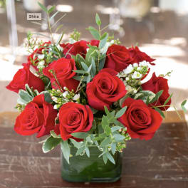 Red roses arranged in a green glass vase with white filler flowers