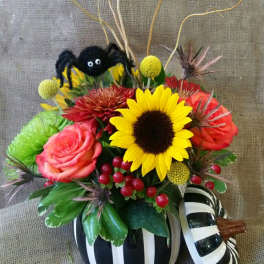 Halloween floral arrangement in a striped pumpkin container with a spider decoration