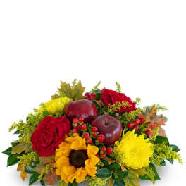 Autumn floral arrangement with red roses, yellow flowers, and decorative apples