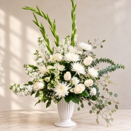 White floral arrangement in a tall white vase with long green stems