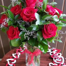 Bouquet of red roses in a clear glass vase with a red ribbon