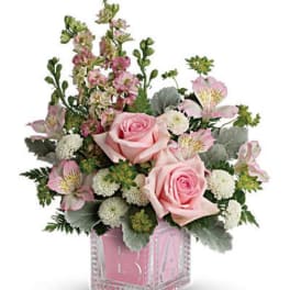 Pink roses and mixed blooms arranged in a clear square vase