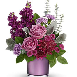Purple and pink flower arrangement in a lavender vase