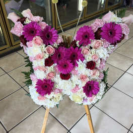 Standing butterfly-shaped floral display with pink gerbera daisies and roses on a wooden easel.