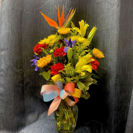 Colorful bouquet of mixed flowers in a glass vase with a pastel ribbon