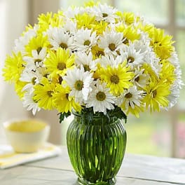 Bouquet of white and yellow daisies in a green glass vase