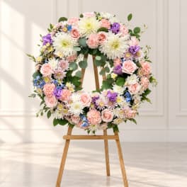 Floral wreath of pink, white, purple, and blue flowers on a wooden easel