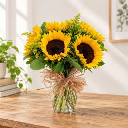 Bouquet of sunflowers in a clear glass vase with a raffia bow