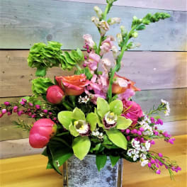 Mixed floral arrangement in a square glass vase with pink and green blooms
