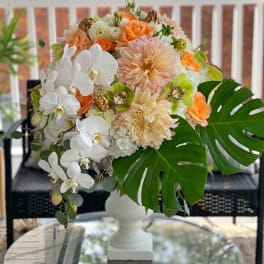 White and peach floral arrangement in a white pedestal vase