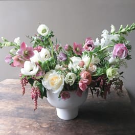Pink and white floral arrangement in a white pedestal vase