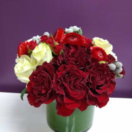 Red and white rose bouquet in a green glass vase