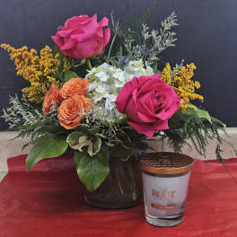 Pink and orange roses in a black vase with a candle beside it