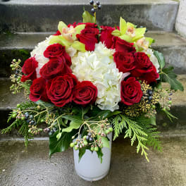 Red roses and white hydrangeas in a white vase with green accents