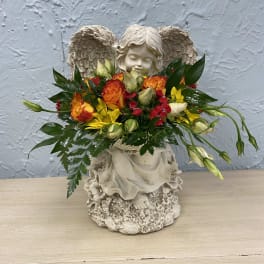 Flower arrangement in a cherub statue with orange, yellow, and red blooms