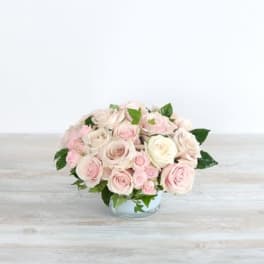 Low bouquet of pale pink and white roses in a clear glass bowl