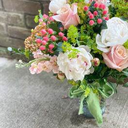Bouquet of pale pink roses, white peonies, and pink blossoms in a vase