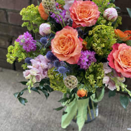 Bouquet of coral roses, purple blooms, and green filler flowers