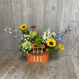 Flower arrangement in an orange container with small garden tools