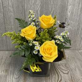Yellow roses with small white daisies in a black vase