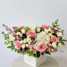 Pink and white rose arrangement in a white wooden box