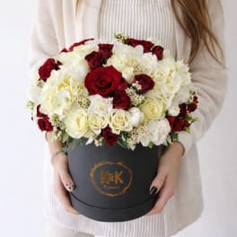 Red and white roses arranged in a black round box