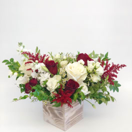 Red and white rose arrangement in a square wooden vase