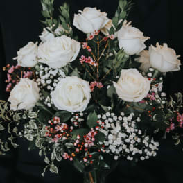 White roses arranged with pink berries and baby's breath