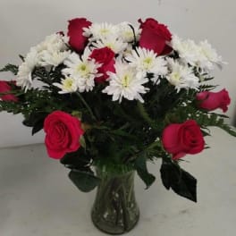 Arrangement of red roses and white chrysanthemums in a clear glass vase