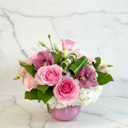 Pink roses and orchids arranged in a pink vase