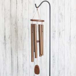 Copper wind chime hanging from a black stand