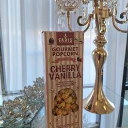 Box of cherry vanilla gourmet popcorn beside a gold crystal candelabra