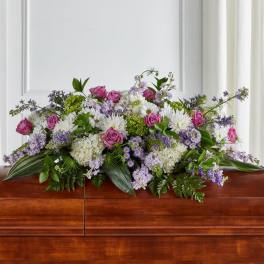 Large floral casket spray with pink roses, white daisies, and purple blooms