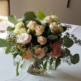 Blush and white roses in a clear glass vase with eucalyptus