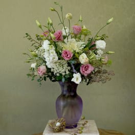 Pink and white mixed bouquet in a purple glass vase