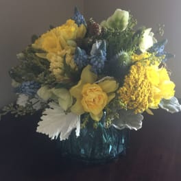 Yellow and blue mixed flower arrangement in a glass vase
