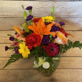 Colorful mixed bouquet in a clear glass vase with lilies and daisies