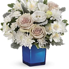 White and blush flowers arranged in a blue glass vase