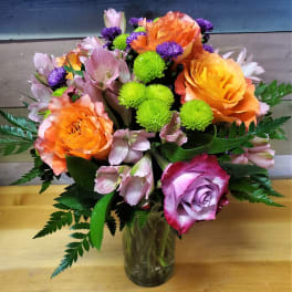 Mixed bouquet of orange and lavender roses with pink alstroemeria in a glass vase