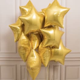 Cluster of shiny gold star-shaped balloons against a light paneled wall