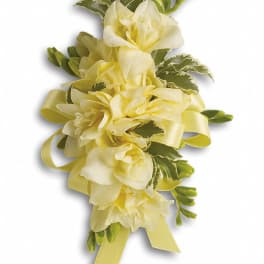 Yellow floral corsage with ribbon and greenery