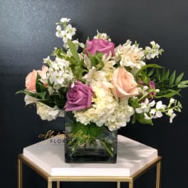 Mixed roses and white flowers in a square glass vase