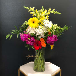 Mixed bouquet in a glass vase with yellow, white, pink, and orange flowers