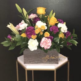 Mixed bouquet of yellow roses, lilies, and carnations in a rectangular box