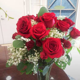 Red roses arranged in a clear glass vase with white baby's breath