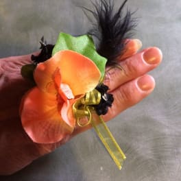 Small orange flower corsage with black feathers and ribbon