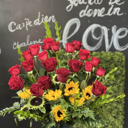 Red roses and yellow sunflowers in a glass vase